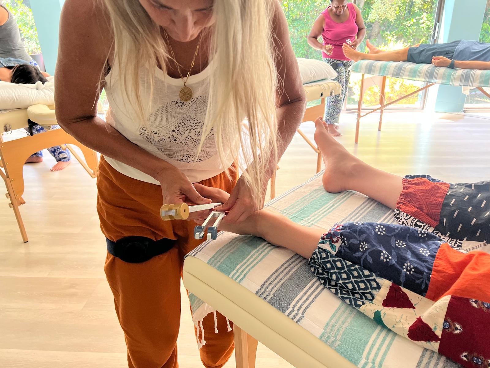 Practitioner activating a tuning fork at the foot during Acutonics practice