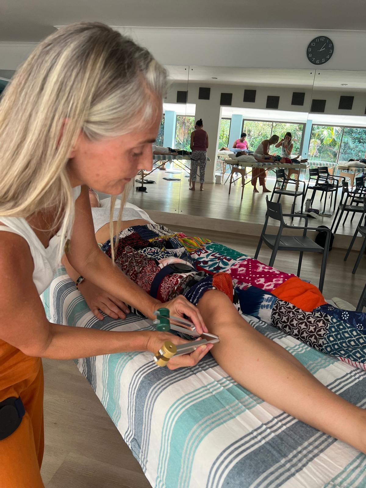 Practitioner applying tuning forks to knee points during Acutonics session
