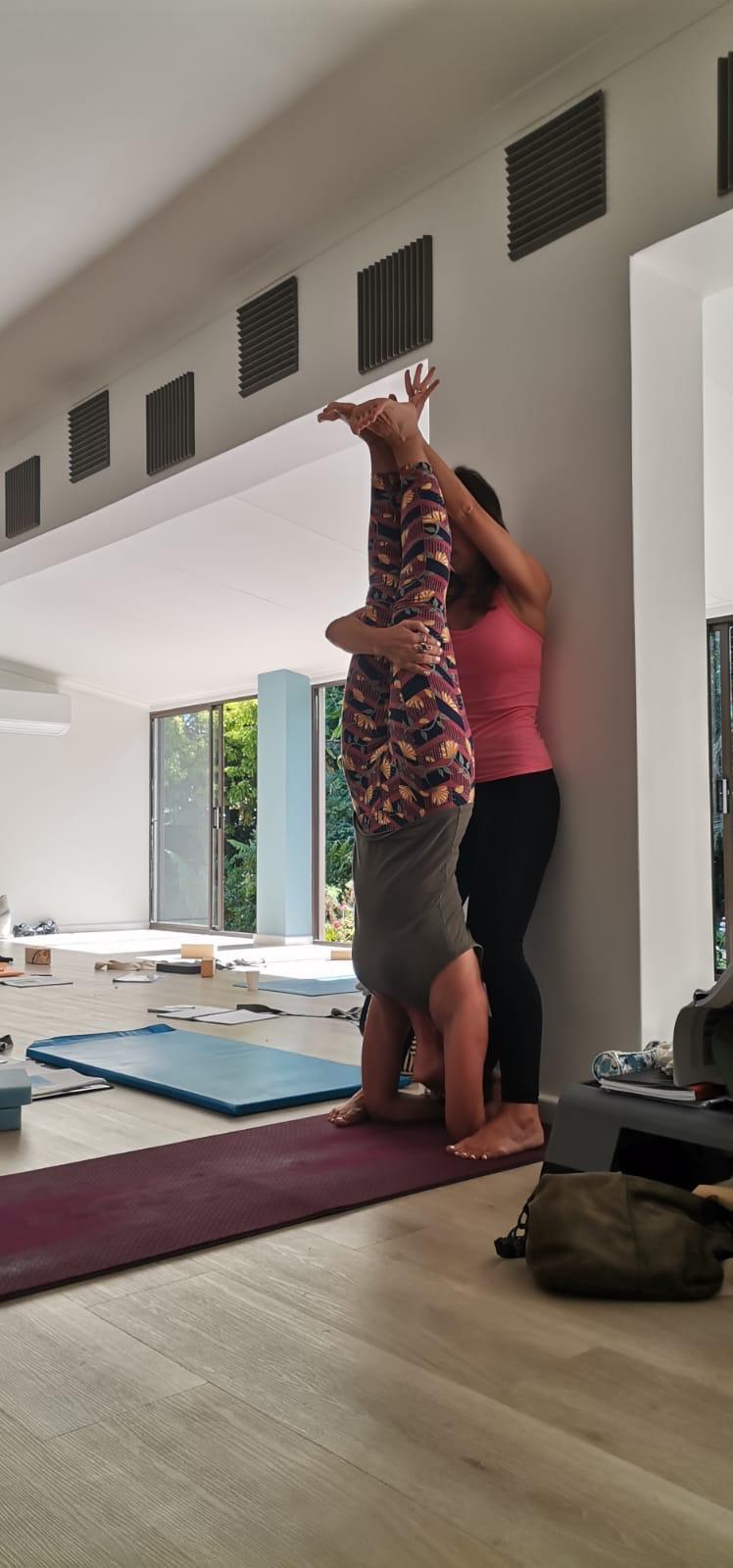 Assisting a student into supported headstand at the wall