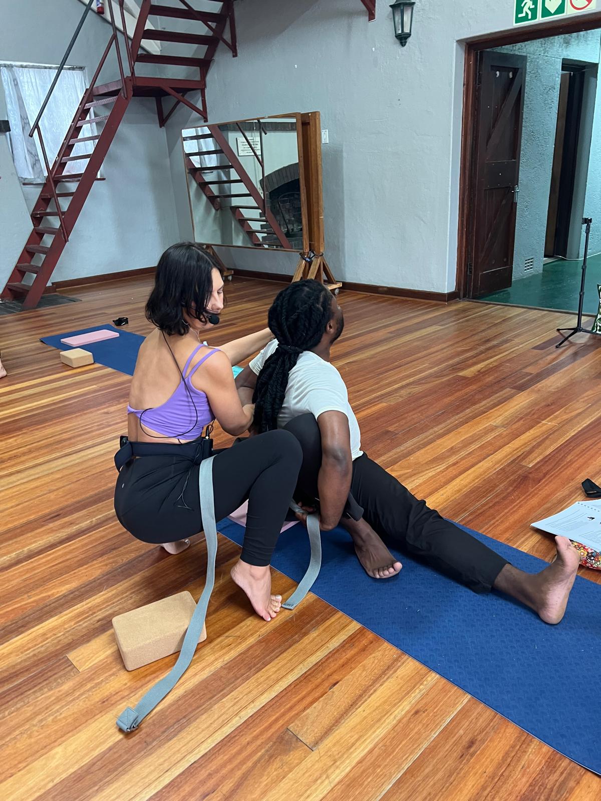 Hands-on adjustment in seated forward bend with a strap
