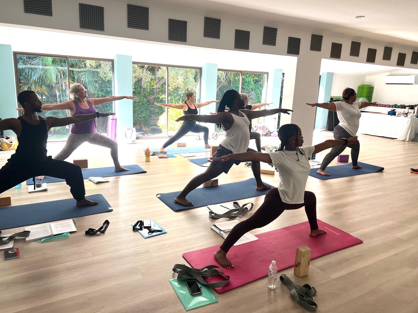 Students practising Warrior II during a 200-hour yoga teacher training class in South Africa